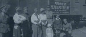 Relief workers, soldiers and children standing close to Near East Relief sign on a train.