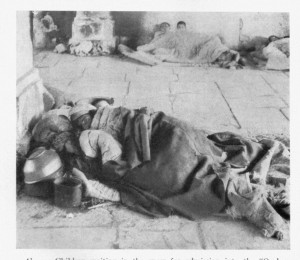 Two Unknown refugees sleeping on the floor, covered with a blanket.