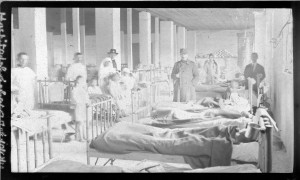 Medical care in Greece. Healing children and helping them to get better and recover sickness. In the picture nurse, doctors and children laying on hospital beds. A person with a suit standing on the right side of the photo.