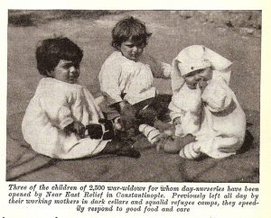 An article with the description of the supplies that are sent to the serve orphans in the nurseries of the Near East Relief. The photo in the article is of three toddlers that are left in the nurseries while their widowed mothers were working.