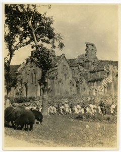 A photo of a house ruins in Alexandropol with children and people walking around it.