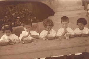 Children at the Birds' Nest say grace before a meal. Antranig Karjian is second from the right. Nellie Miller's original caption reads: 