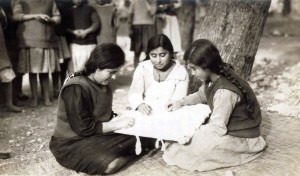 Three young women embroider together while seated on the ground. Sewing was a marketable skill for orphanage graduates.
