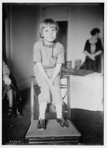 Jackie Coogan the child film star, sitting on the back of a chair.