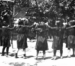Girls in black dresses dancing in courtyard. Dancing was a means of preserving cultural heritage.