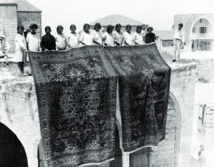 Women and girls standing and holding handmade rug.