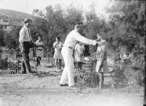 A male relief worker helping a young orphan girl to pose for a photographer. From the photo, it appears that the photographer was taking portraits of several orphans.