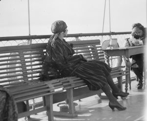 Unidentified well-dressed woman on a ship's deck. Based on her clothing, the woman is probably a relief worker or the wife of a Near East Relief worker. This negative is part of a series that includes views of refugees on a ship deck. Those photos were probably taken from this upper deck, looking down at the crowd. 