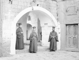 Three Orthodox priests standing in a church courtyard. 