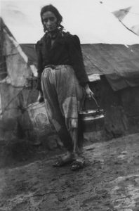 A refugee woman carries water through a refugee camp
